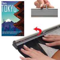 By hand, simply snap open both snap bar rails, top and bottom, slide graphic or poster in, and snap close 